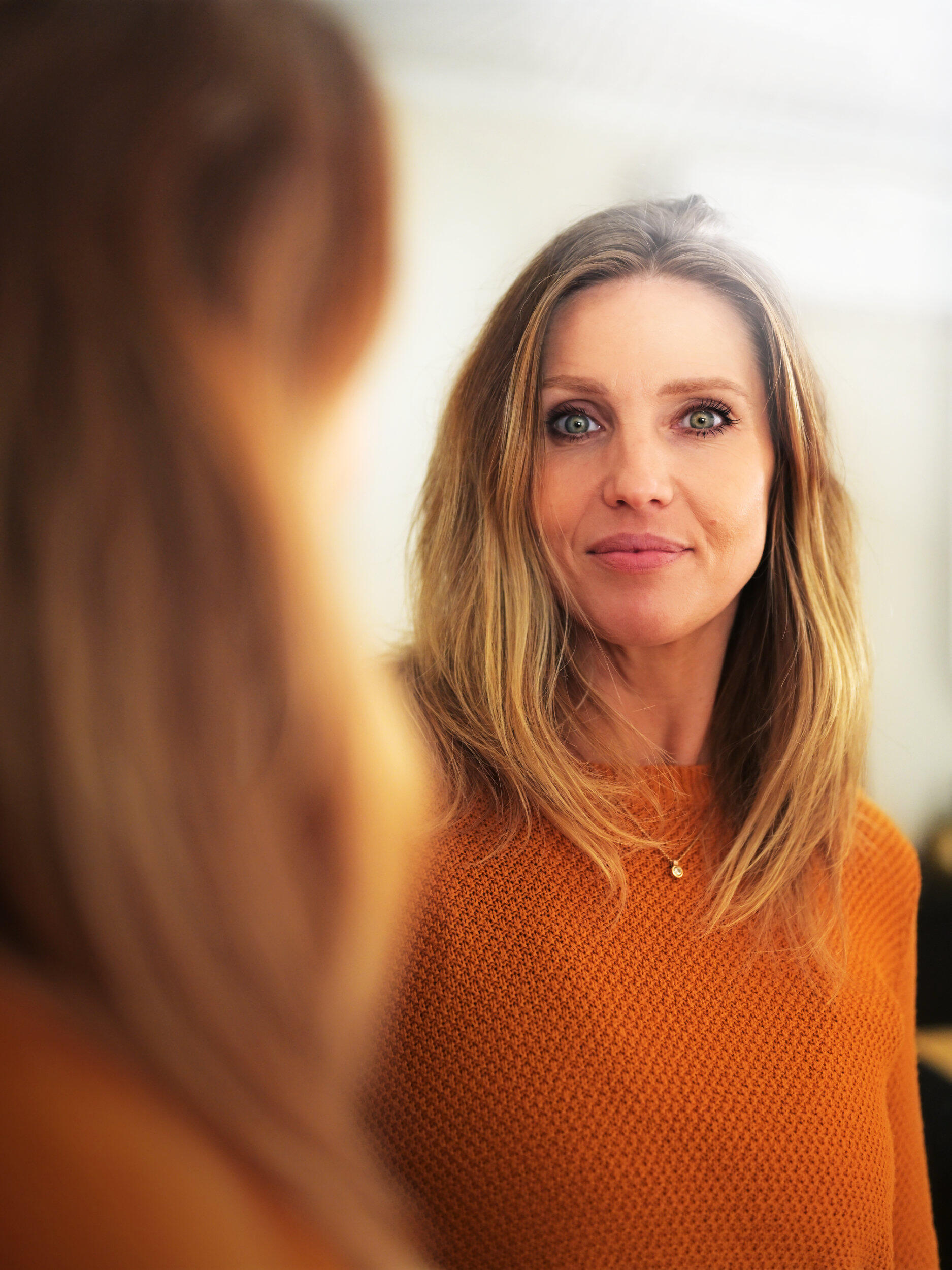 A beautiful woman in front of a mirror with piercing green eyes and a warm glow